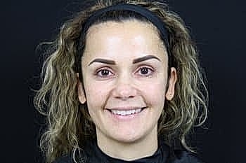 Smiling person with curly hair against black background