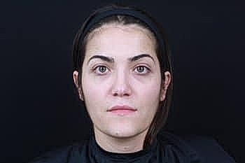 Woman with neutral expression on dark background.