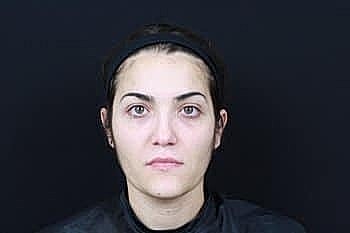 Woman with natural makeup in front of black backdrop.