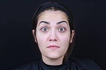Woman with surprised expression against dark background.