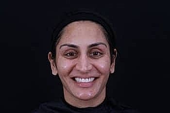 Smiling woman with natural makeup on black background.