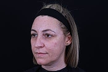 Woman with headband against black backdrop.