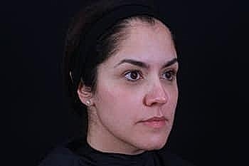 Woman with neutral expression against dark background.