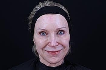 Woman with light makeup against dark background.