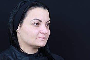 Woman with long black hair against dark background.