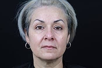 Woman with silver hair against dark background.