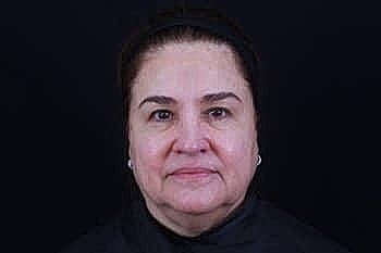 Woman with neutral expression against dark background.