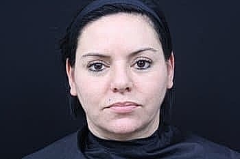 Woman with dark hair against black background.