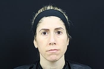 Woman with neutral expression against dark background