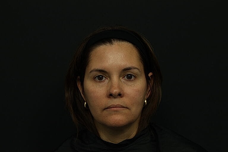 Woman with serious expression against dark background.