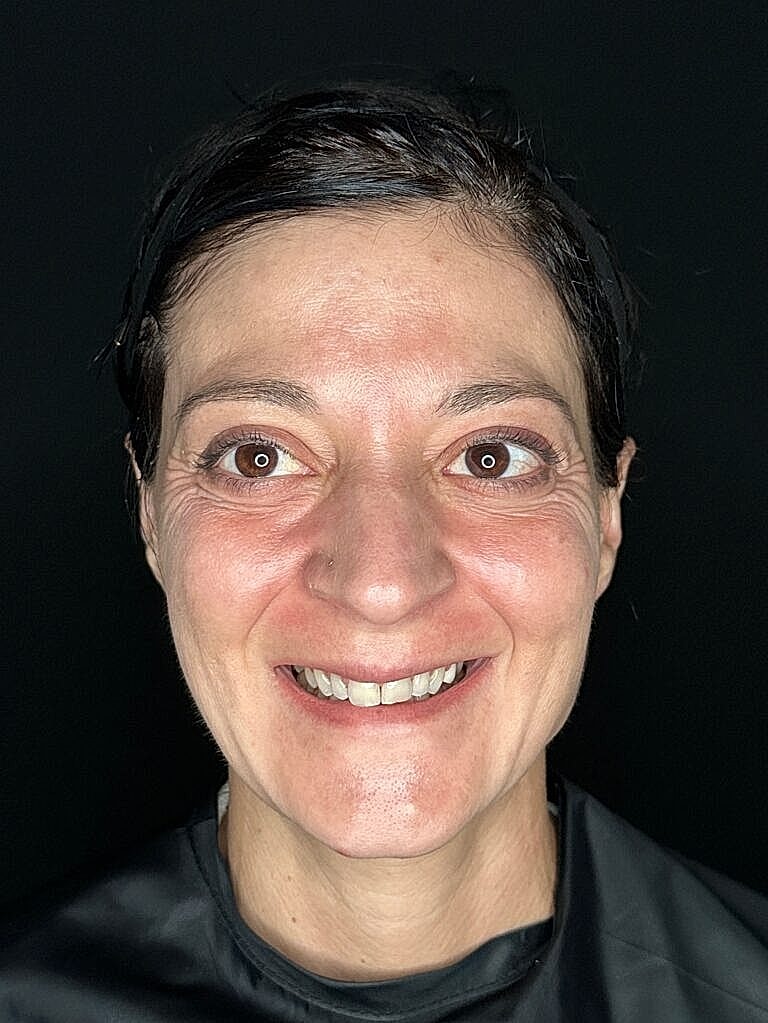 Smiling woman with dark background, close-up shot.