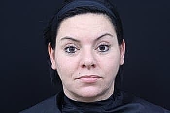 Woman with neutral expression in black backdrop.