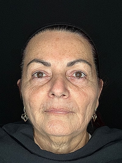 Elderly woman with natural makeup and earrings.