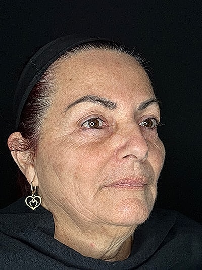 Woman with earrings, serious expression, dark background.