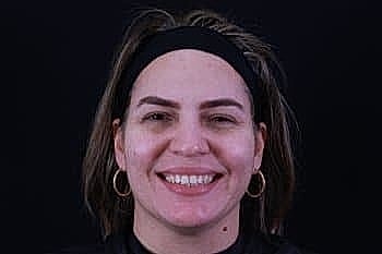 Smiling woman with hoop earrings and headband.
