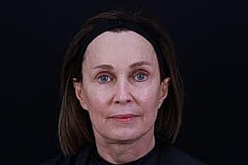 Woman with brown hair against a black background.
