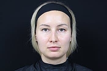 Woman with short blonde hair against dark background.