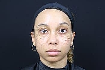 Person with artful facial markings against dark background