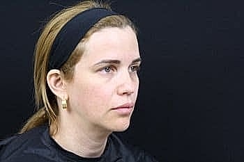 Woman with headband against black background.