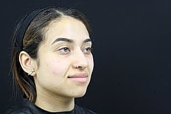Woman with natural makeup against black background.
