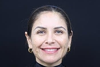 Smiling woman against a dark background.