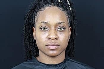 Person with braided hair against dark background.