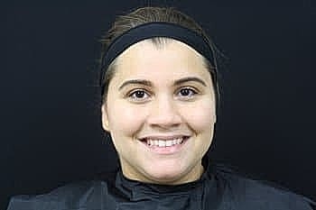 Smiling woman in salon attire against black background