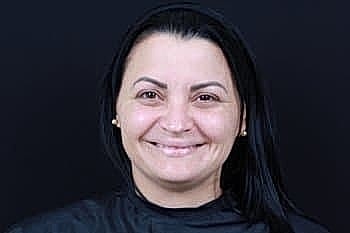 Smiling woman with long black hair and earrings.