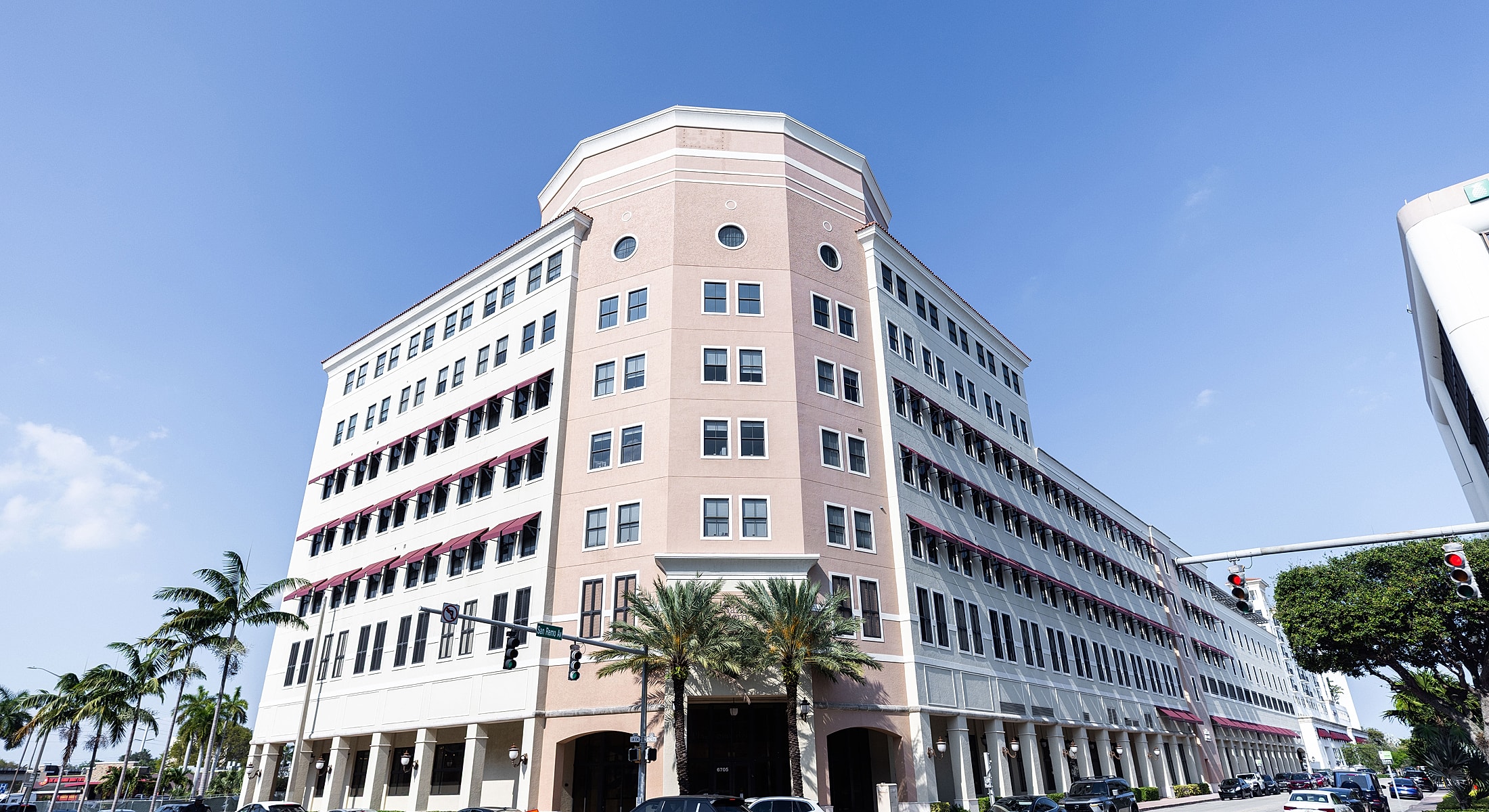 Modern building with palm trees and blue sky.
