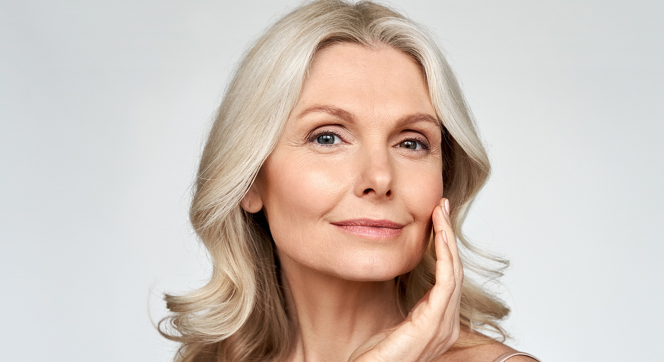 Woman with silver hair touching her face.