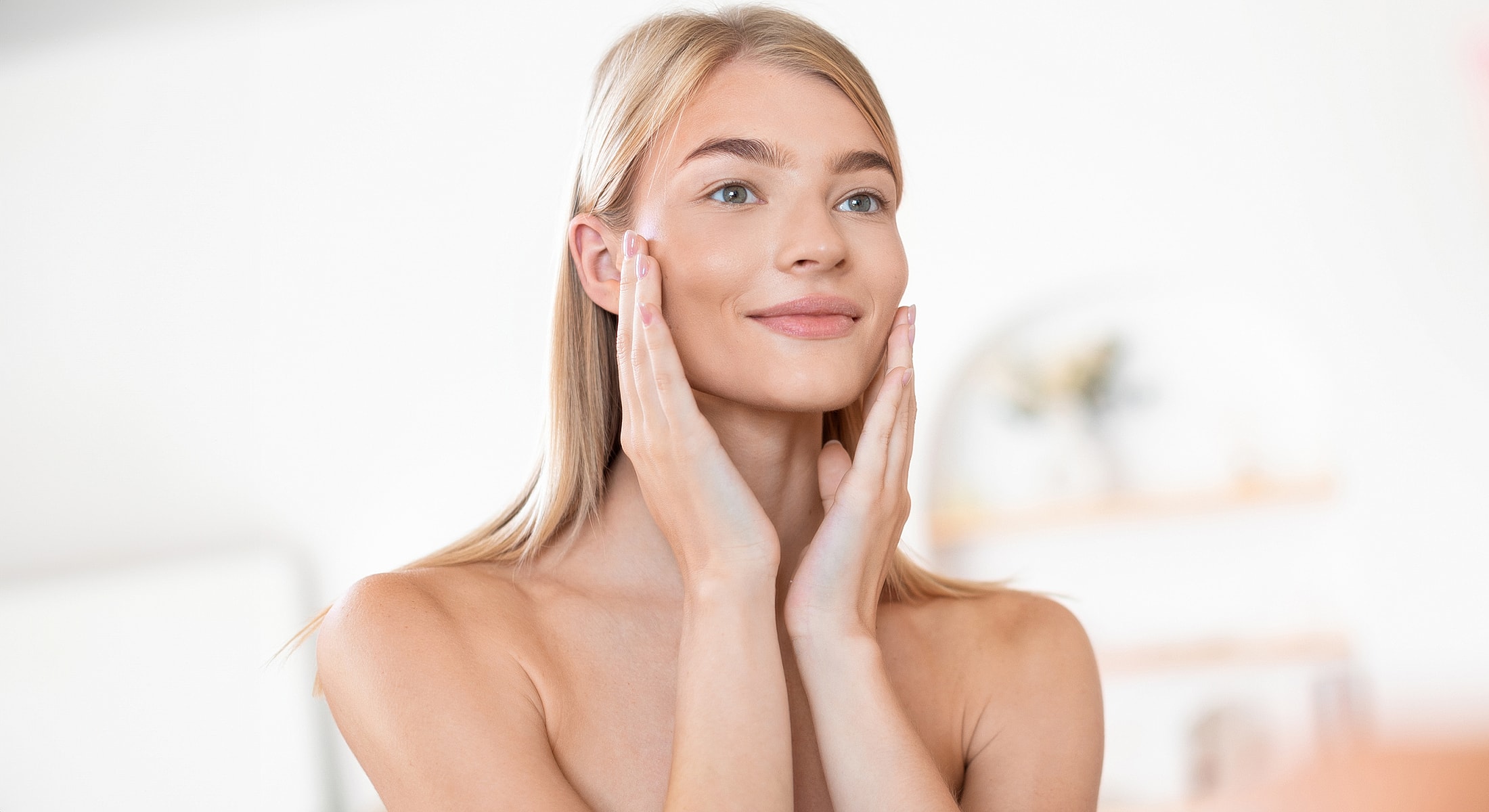 Woman applying skincare in bright setting.