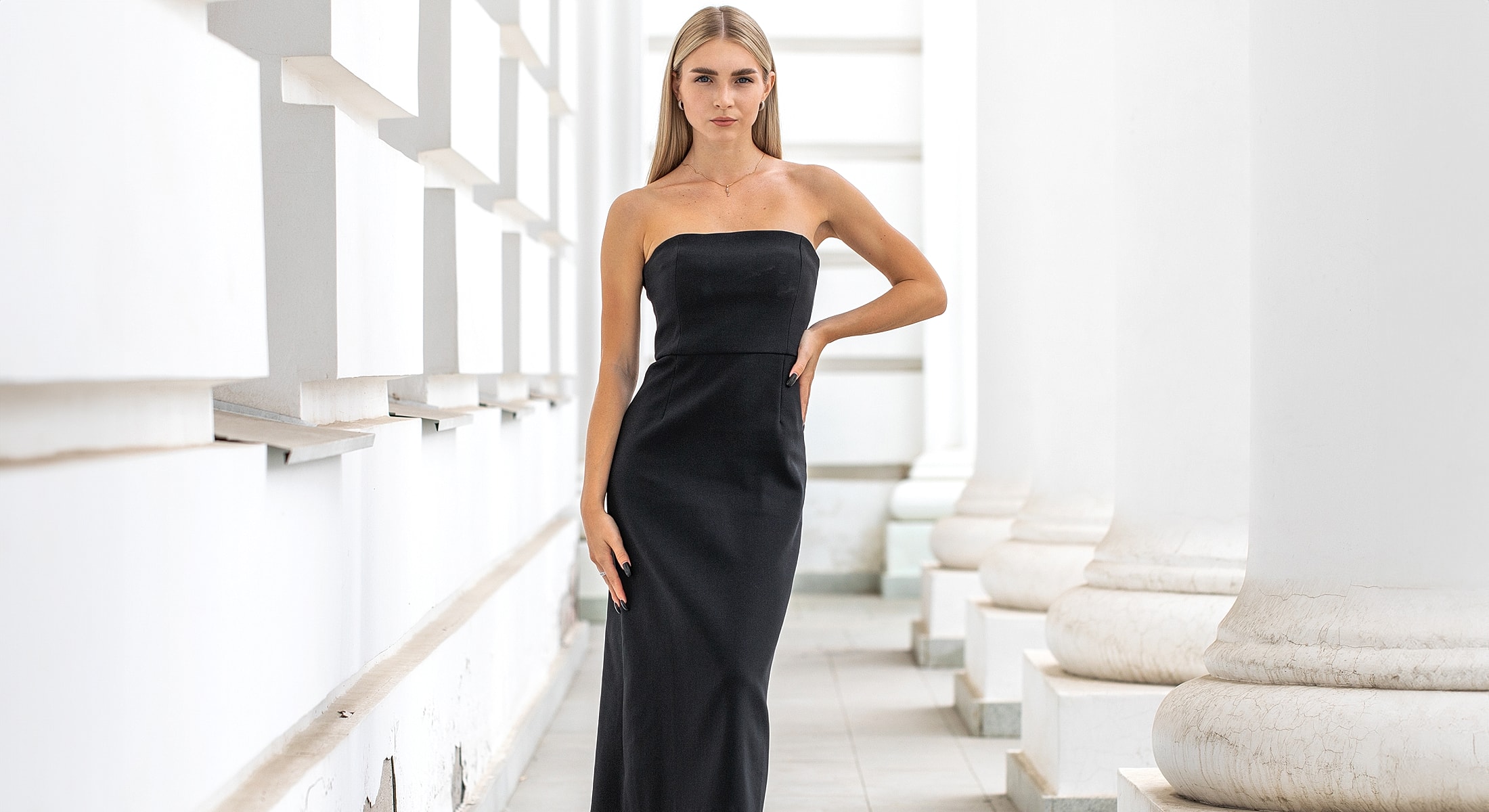 Model in a strapless black dress indoors.