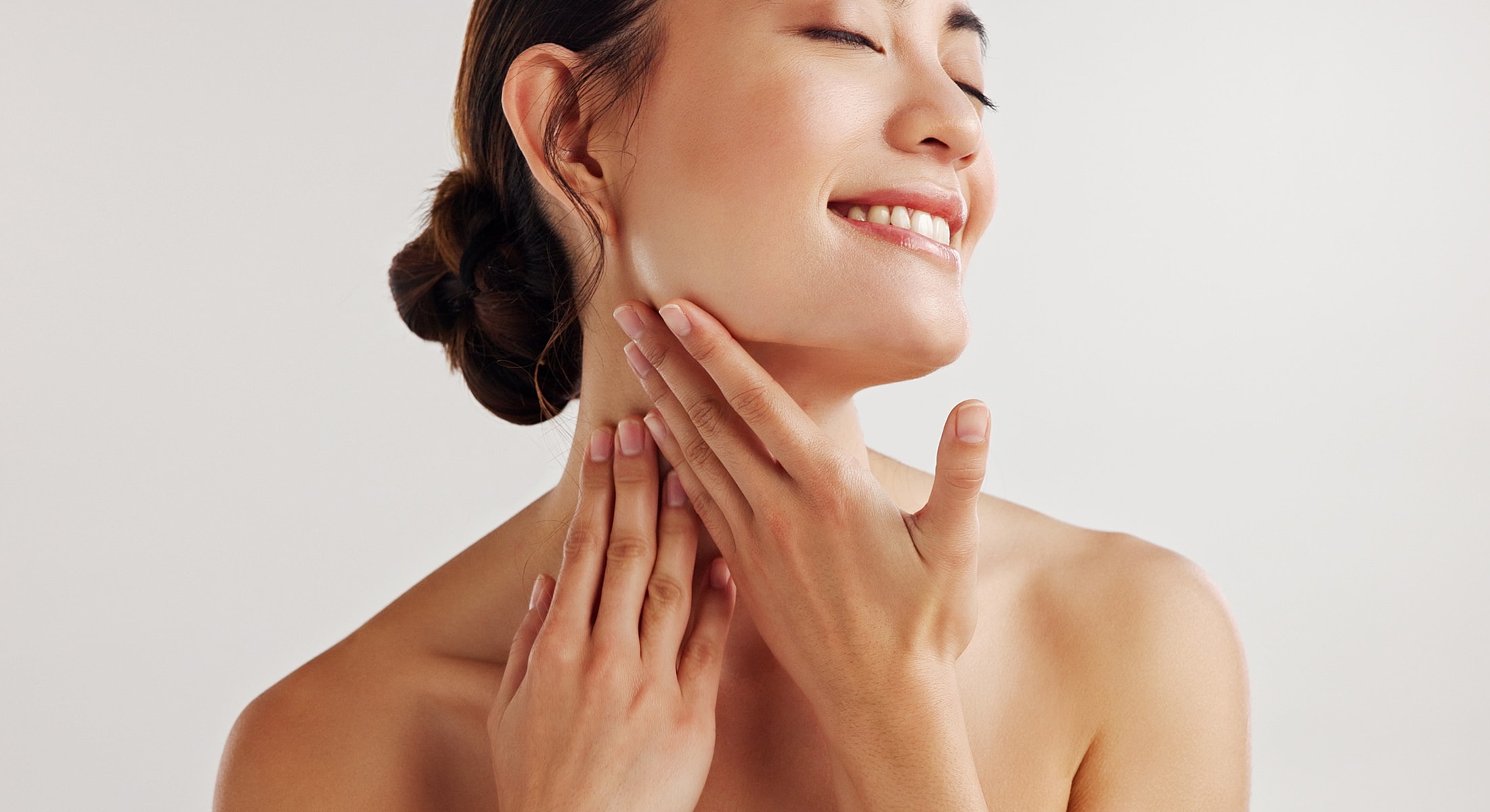 Woman gently touching her face, smiling softly.